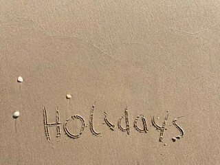 Fototapeta premium on the beach is carved with letters in the smooth sand the writing holidays