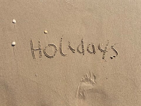 on the beach is carved with letters in the smooth sand the writing holidays