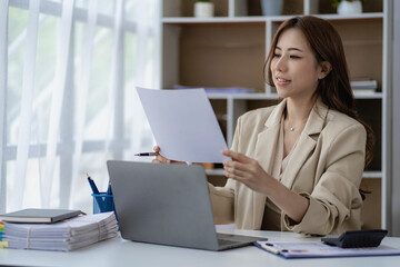 Asian businesswoman working on laptop computer and graph planning financial report analysis strategy business plan investment concept of financial analysis in modern office