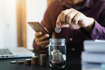 Men hand puting coins in glass for saving money. concept finance and accounting in the home.