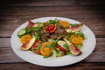 Recipe for fried chicken liver and gizzards with salad and tomatoes, cucumber, figs, grapes on a white plate, High quality photo