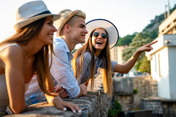 Happy group of young friends enjoying sightseeing tour in the city on summer vacation.