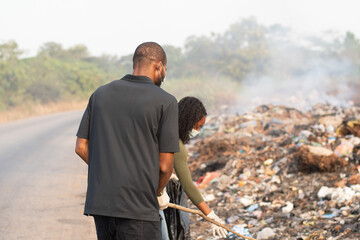 african man and woman cleaning a refuse site