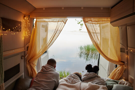 Friends lying in camper van and looking at lake