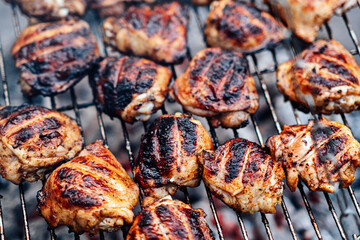 Grilled Chicken Thighs on charcoal grill outdoors. BBQ Chicken. Frilling bone-in chicken legs, thighs