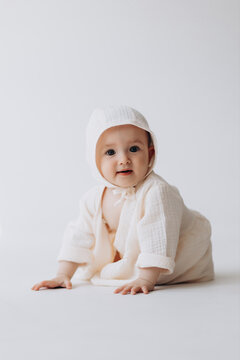 Cute studio portrait of a little newborn girl posing for a photo on a light background. A baby who has already learned to crawl and sit