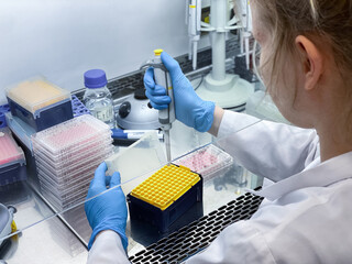 A female scientist performing an biological experiment using a pipette. Pipettes are used for...