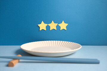 三ツ星と皿と箸と青背景の中央配置の写真