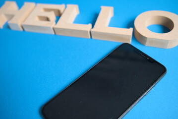 スマートフォンとハロー文字と青背景の右寄りの写真