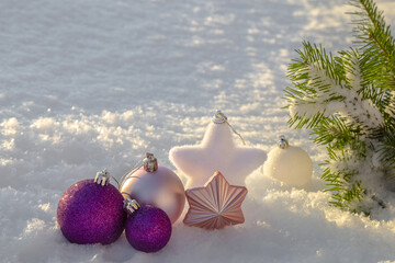 Purple and pink Christmas decorations in the snow.