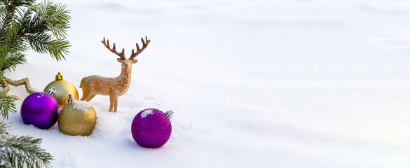 Banner with purple and gold Christmas decorations on the snow.