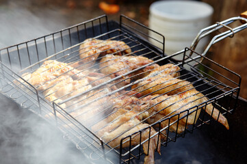 Tasty chicken wings cooking on barbecue grill, outdoors. Roasted chicken meat, closeup