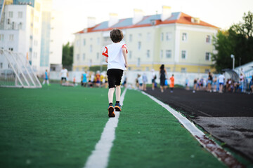 The child goes in for sports at the stadium. The boy is training before playing football.