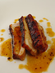 Crispy Pork Belly on a White Plate With Juices