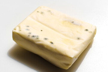 a pack of spoiled butter with mold on a white background. 