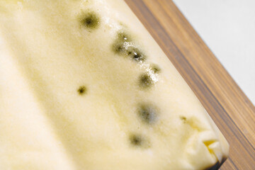 part of a pack of spoiled butter with mold on a wooden board