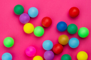 Abstract colored balls background. Multi-colored taw toy scattered on bright paper. Base for design nice backdrop, wallpaper, poster. Noisy surface texture