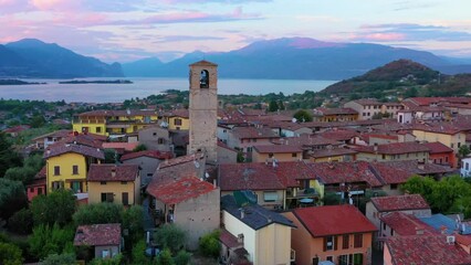 Aerial view of village near Lago di Garda Italy. Beautiful sunset light. Flying close to the church tower revealing Lago di Garda on the horizon. Manerba del Garda town in Brescia Italy.  