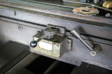 Position adjustment handle lever of the CNC lathe machinery working bench. Industrial equipment and object photo, selective focus at the handle part.