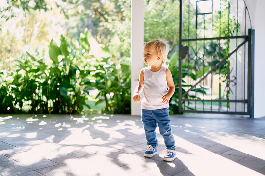 Little girl standing on the tiled floor in the patio. High quality photo