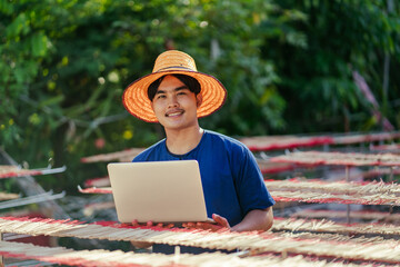 Portrait indigenous young Asian man SME business owner working use computer laptop for e-commerce...