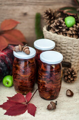Still life with dried tomatoes in jars, autumn leaves, cones and acorns, warm scarf, apples closeup.