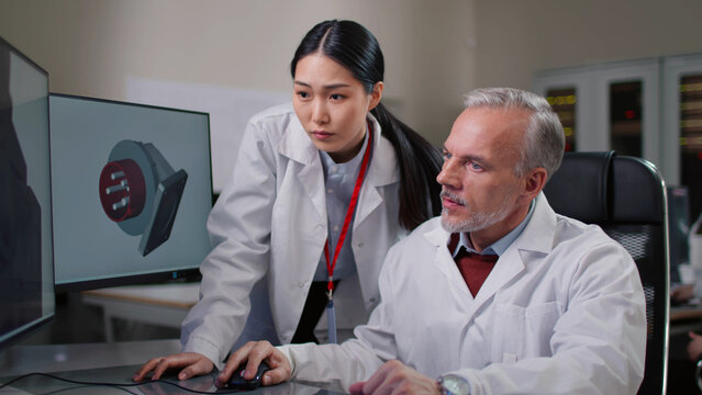 Diverse engineers in lab coats discuss design of 3d model on computer