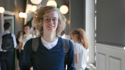 Young happy smiling high school student standing in campus looking at camera. 