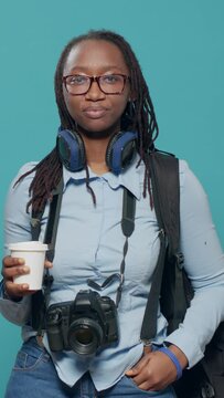 Vertical video: Traveler photographer going on holiday trip to take pictures with camera and photography equipment. Holding coffee cup and backpack to travel on vacation and take photos over
