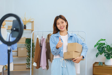 Online shopping concept, Young Asian women hold parcel boxes and thumbs up while looking at camera