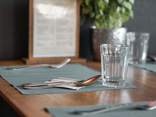 Drinking glass and cutlery on a table in a restaurant, selective focus, blurred effect
