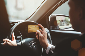 Businessman hands holding credit card in the car instead of cash.