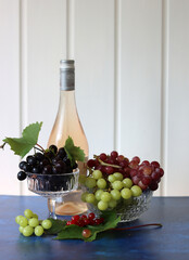 Still life with wine and grapes. Colorful photo of bottle of rose wine and different sorts of...