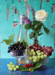 Still life with wine and grapes. Colorful photo of bottle of rose wine and different sorts of...