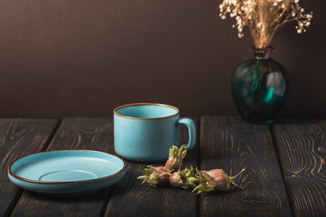 Hazelnuts and a blue cup on a wooden dark background.