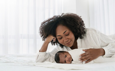 Close up portrait of beautiful young African American mother holding sleep newborn baby in...