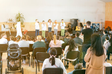 Children on the stage. Children on stage perform in front of parents. Young talents on stage. Children stand in front of parents in school. Blurry. toned