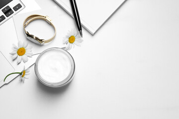 Flat lay composition with jar of hand cream and chamomiles on white table, space for text