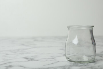 Empty glass jar on white marble table, space for text