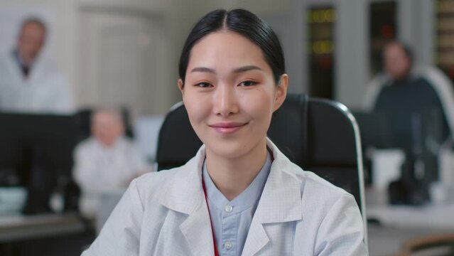 Portrait of young asian woman doctor smiling at camera sitting in office