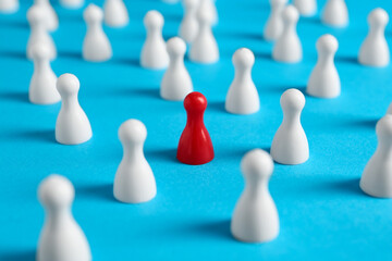 One red pawn among others on light blue background, closeup. Social inclusion concept