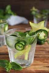 Spicy cocktail with jalapeno, carambola and mint on wooden table