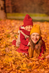 Laughing mother and daughter playing and laughing on autumn walk. Happy woman with little daughter having fun at autumn. 