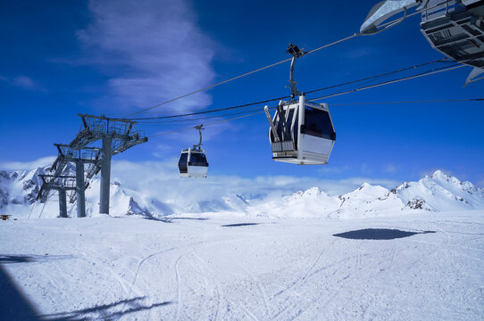 Funitel aerial lift in snow mountains against blue sky with clouds in bright winter day