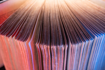 a thick book is opened in a semicircle. Red and blue decorative lighting