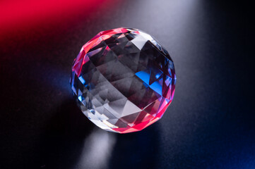a crystal faceted ball shimmers with blue-red highlights on a dark background.