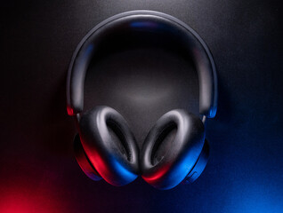 Fototapeta na wymiar Black headphones on a black background. Blue and red creative backlight.