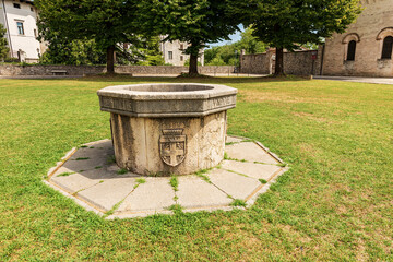 Ancient medieval stone water well in Spilimbergo downtown, in front of the Cathedral of Santa Maria...