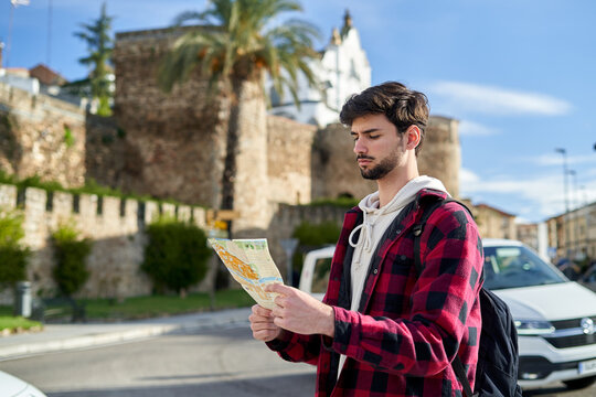 Traveling man with suitcase checking map