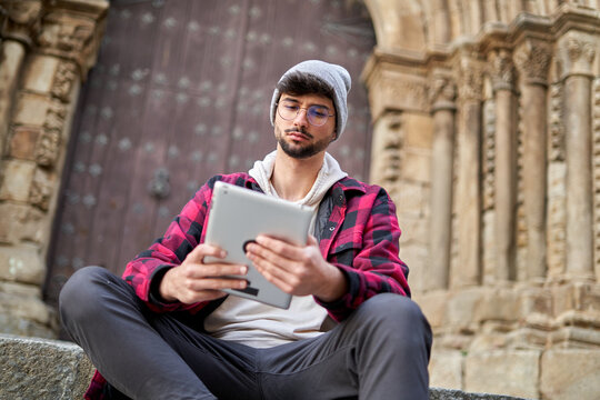 Hipster browsing tablet on stairs of old building